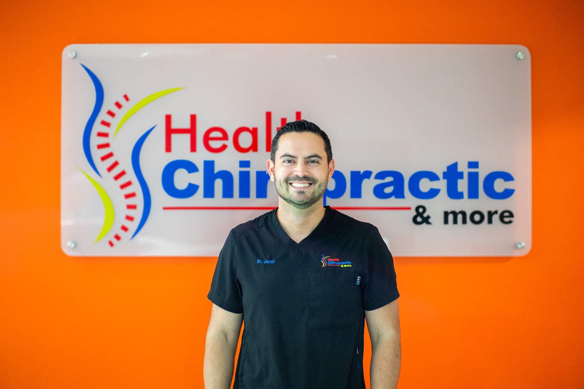 Dr. Jarrot frente al logo de Health Chiropractic & More